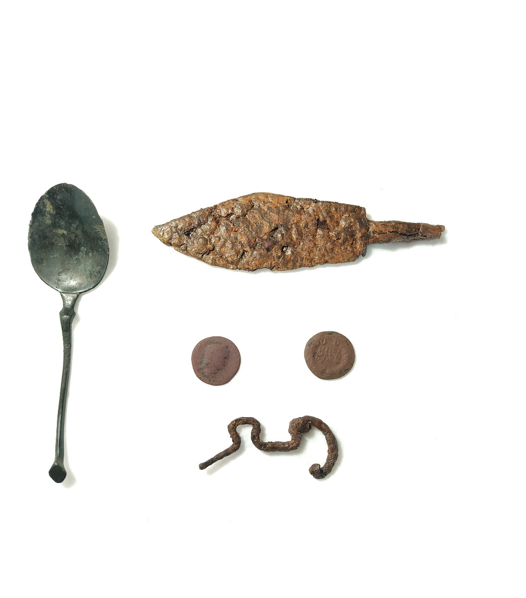 Pannello 2 - Foto 4: Fibula da Rocca Pia (Età del Ferro, VI-V sec. a.C.), cucchiaio e monete (epoca romana, I-III sec. d.C.), coltello (IV sec. d.C.) | conservati presso la Fondazione MCR